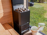 Saunum Air L 15 heater loaded with stones beside a window overlooking a green lawn
