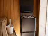 Saunum Air L 15 heater in a cedar and marble sauna corner with white pail and ladle