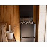 Saunum Air L tower heater standing in a warm cedar sauna interior with bucket