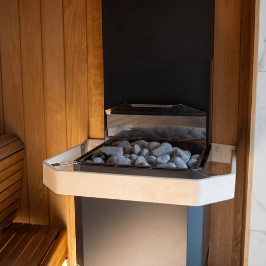 Angled view of the Saunum Air L heater stone tray filled with gray sauna stones