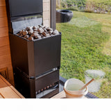 Saunum Air L heater topped with stones beside a sauna bucket and garden window