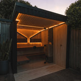 Saunum Air L heater installed in a backlit outdoor sauna cabin at dusk