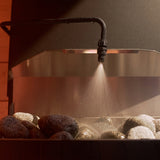Saunum Auto Leil nozzle misting water over warm sauna heater stones