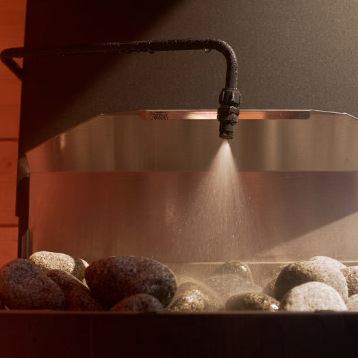 Saunum Auto Leil nozzle misting water over warm sauna heater stones