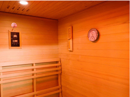 Interior of the SunRay Bristow sauna with wall-mounted control panel, sand timer, round thermometer-hygrometer and bench backrest