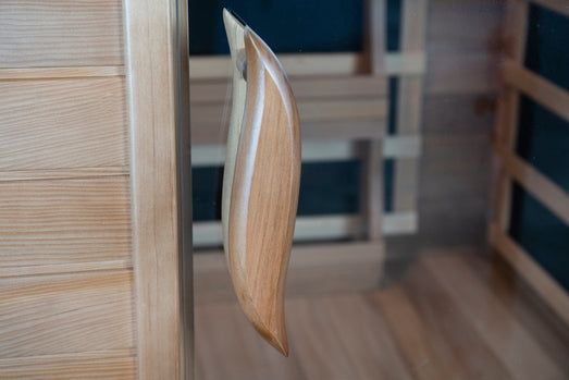 Curved wooden door handle on the glass door of the SunRay Sedona infrared sauna