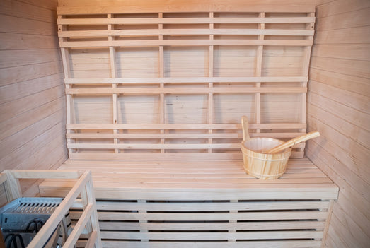 SunRay Waverly sauna bench and backrest with a wooden bucket and ladle, heater guard in the corner