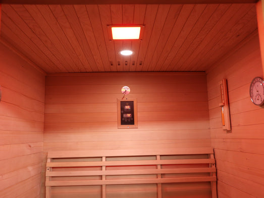 Interior of the SunRay Waverly sauna with bench, control panel on the back wall, ceiling lights, sand timer and thermometer-hygrometer