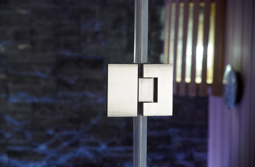 Glass door hinge of the SunRay Westlake sauna with the slate-colored stone wall and slatted lamp behind